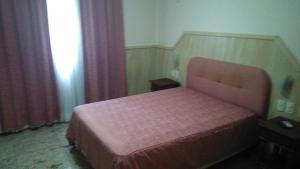 ein Schlafzimmer mit einem rosa Bett und einem Fenster in der Unterkunft Villa Norma Suites in Vitória