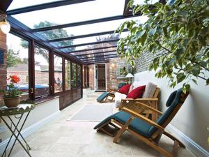 a conservatory with a chair and a couch in a room at The Hamlet in Cromer +3 photos