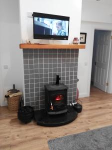 a fireplace with a tv on top of it at Elm Cottage in Cong