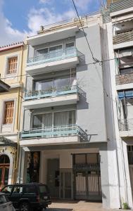 a white building with balconies and a car parked in front at MADONAS HOUSE PSIRI in Athens