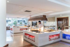 Hotel Sun Palace Albir & Spa في البير: طباخ يحضر الطعام في مطبخ كبير