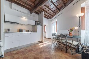 ローマにあるBlack White - FromHometoRomeの白いキャビネット、テーブルと椅子付きのキッチンが備わります。