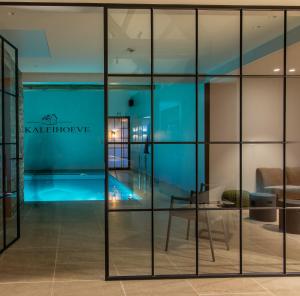 BavikhoveDe Kaleihoeve的一间设有玻璃墙的房间和一个游泳池