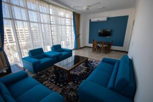 een woonkamer met blauwe banken en een tafel bij Home Station Hotel in Muscat