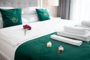 uma cama branca com toalhas e um vaso de flores em GA Luxury Apartments M45 em Cracóvia