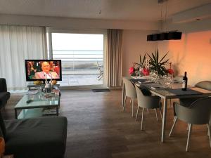 a living room with a table with chairs and a television at Penthouse Poseidon in Blankenberge +27 photos