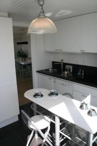 a white kitchen with a white table and chairs at Penthouse Poseidon in Blankenberge