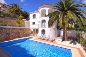 a villa with a palm tree and a swimming pool at Villa Paz in Benissa