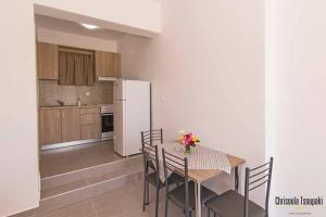 a kitchen with a table and chairs and a white refrigerator at Votsalo Studios & Apartment in Frangokastello