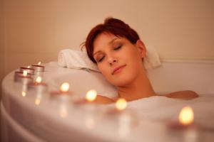 a woman laying in a bath tub with candles at Elliott House Boutique Inn in Shaver Lake