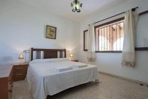 a bedroom with a white bed and a window at Villa Marifina in Benissa