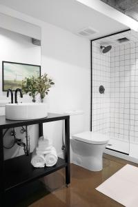 La salle de bains blanche est pourvue d'un lavabo et de toilettes. dans l'établissement Maison Sainte-Thérèse By Maisons & co, à Montréal