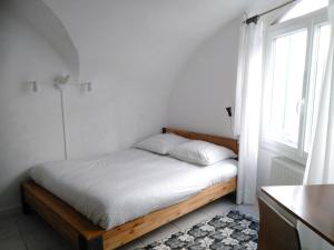 uma cama num quarto branco com uma janela em Studio - Fontaine em Saint-Paul-Trois-Châteaux
