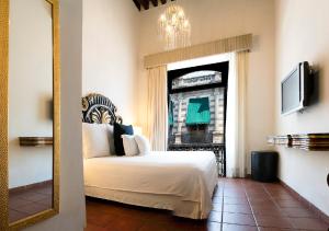 Habitación de hotel con cama y espejo en Hotel Herencia By Hosting House en Morelia