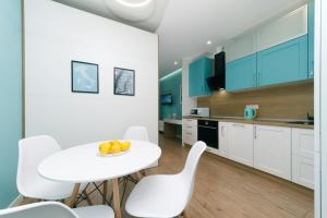 eine weiße Küche mit einem weißen Tisch und weißen Stühlen in der Unterkunft Happy apartment, warmth, comfort, turquoise in Kiew