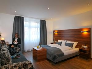 a woman in a hotel room with a bed and a couch at Schlotzeria Hotel I Café I Eis in Grenzach-Wyhlen