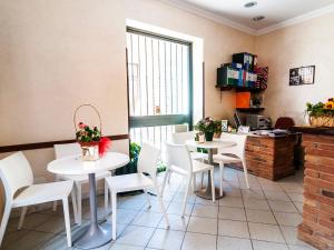 a restaurant with white tables and white chairs and a window at La Casa degli Artisti 1 in Nettuno