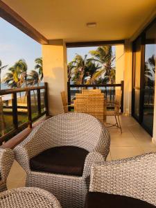 a balcony with two wicker chairs and a view of the ocean at Wai Wai Cumbuco Eco Residence in Cumbuco