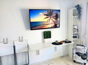 a living room with a tv on the wall at Pure BLISS Luxury Beachfront Apartment with Panoramic Sea Views, Electric BBQ and More in Agia Triada