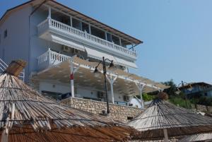 un gran edificio blanco con balcón y sombrillas en Hotel Te Stefi, en Qeparo