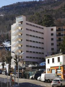 a large white building with cars parked in a parking lot at STUDIO COSY LE ROYAL SKI 3 VALLÉES in Brides-les-Bains