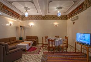 a living room with a table and a television at Kasbah Sirocco in Zagora