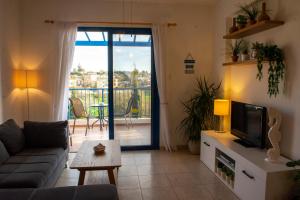 salon z kanapą i telewizorem oraz balkonem w obiekcie Ron’s Pergola Apartment w Pafos
