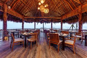 un restaurant avec des tables et des chaises et un grand plafond dans l'établissement Mystique Holbox by Royalton, A Tribute Portfolio Resort, à Holbox