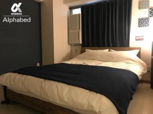 - une chambre avec un lit et une couverture noire et blanche dans l'établissement Alphabed Takamatsukouzaiekimae 102 / Vacation STAY 20340, à Takamatsu