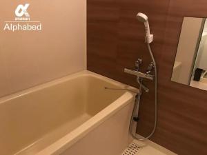 La salle de bains est pourvue d'une baignoire et d'une douche. dans l'établissement Alphabed Takamatsukouzaiekimae 102 / Vacation STAY 20340, à Takamatsu