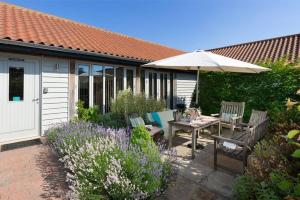 un patio con ombrellone, tavolo e sedie di Lackford Lakes Barns a Flempton