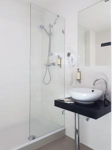 a white bathroom with a sink and a shower at Chopin Apartments - Eco in Warsaw