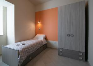1 dormitorio pequeño con 1 cama y pared de color naranja en La Madonnina, en Nicosia
