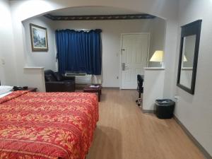 um quarto de hotel com uma cama vermelha e uma cadeira em Scott Inn & Suites - Downtown Houston em Houston