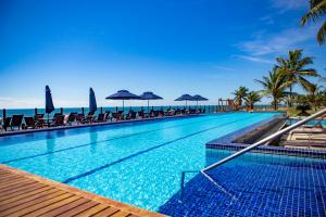 a swimming pool with chairs and umbrellas on the beach at Excelente casa, pé na areia, no melhor de Arraial! in Arraial d'Ajuda