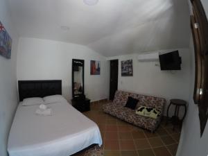 a hotel room with a bed, couch and a television at Hosteria El Castellano in Santa Fe de Antioquia