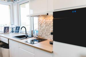 a kitchen with white cabinets and a black refrigerator at Warszawska 15 Apartament in Gdynia