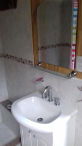 lavabo blanco en el baño con espejo en Cabañas Villa Centauro en San Carlos de Bariloche