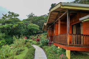 una casa de madera con un camino al lado en Heliconias Rainforest Lodge en Bijagua