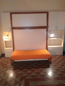 1 cama naranja en una habitación con 2 estanterías en Casa indipendente, en Fiumefreddo di Sicilia