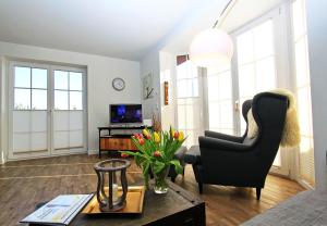 una sala de estar con una silla y una mesa con flores en Haus-Clara en Hörnum