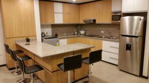 eine Küche mit einem Kühlschrank und einer Theke mit Stühlen in der Unterkunft Condominio La Victoria, Departamento en Cuenca 4 in Cuenca