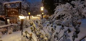 a snow covered street at night with a sign and trees at De las Rosas Bariloche in San Carlos de Bariloche