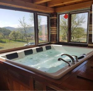 eine große Badewanne in einem Zimmer mit Fenstern in der Unterkunft Ranch Diamond Sarajevo in Vogošća