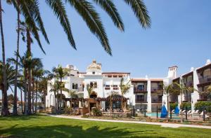 a large white building with palm trees in the foreground at Santa Barbara Inn in Santa Barbara