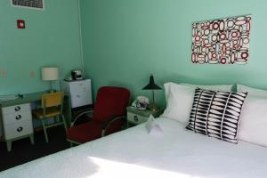a bedroom with a bed, desk, chair, and lamp at Holiday Music Motel in Sturgeon Bay