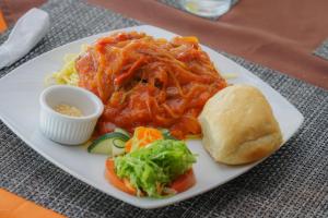 un plato de comida con pasta y verduras y un sándwich en Heliconias Rainforest Lodge, en Bijagua