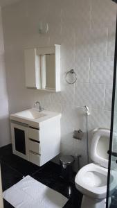 a white bathroom with a toilet and a sink at Suítes Xodo Tour in Arraial do Cabo