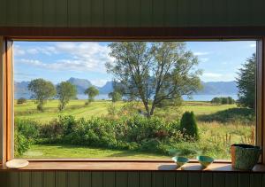 a window with a view of a field and trees at Bø Huset in Sortland