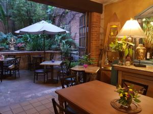 un restaurant avec des tables, des chaises et un parasol dans l'établissement Casa Embrujo Morelia - Boutique, à Morelia